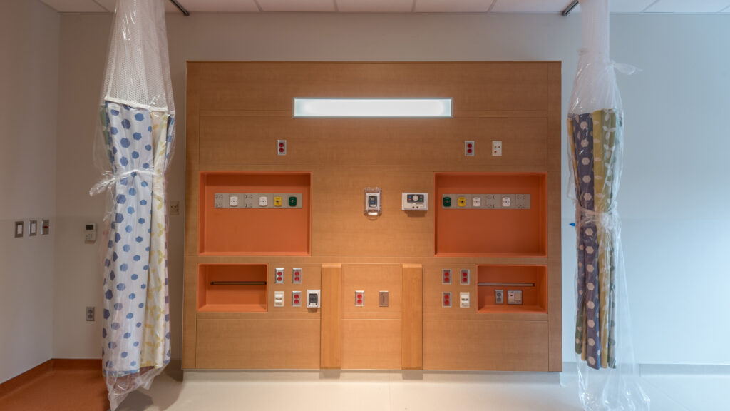 A hospital room looking at the headwall with outlets and receptacles.